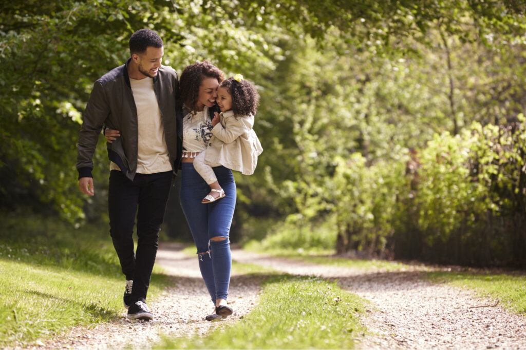 A family of three walking through some woods