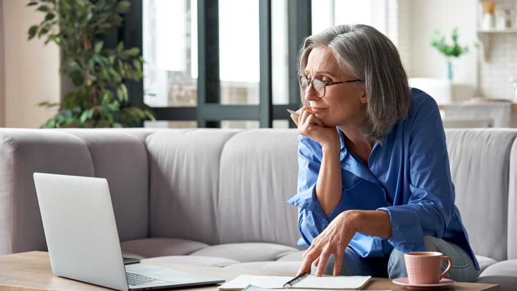 An older woman working on a laptop.