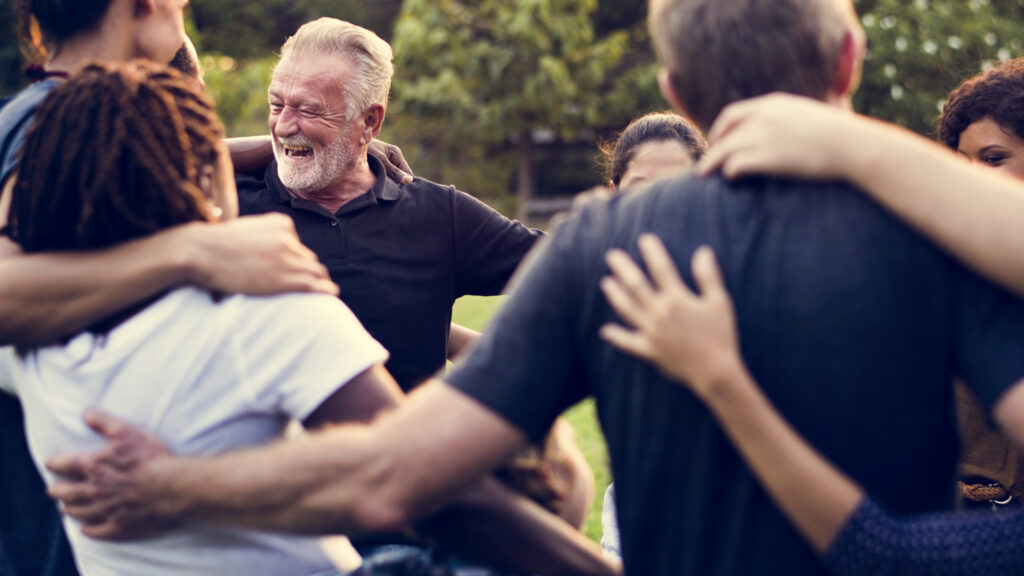 A group of people with their arms around each other laughing.