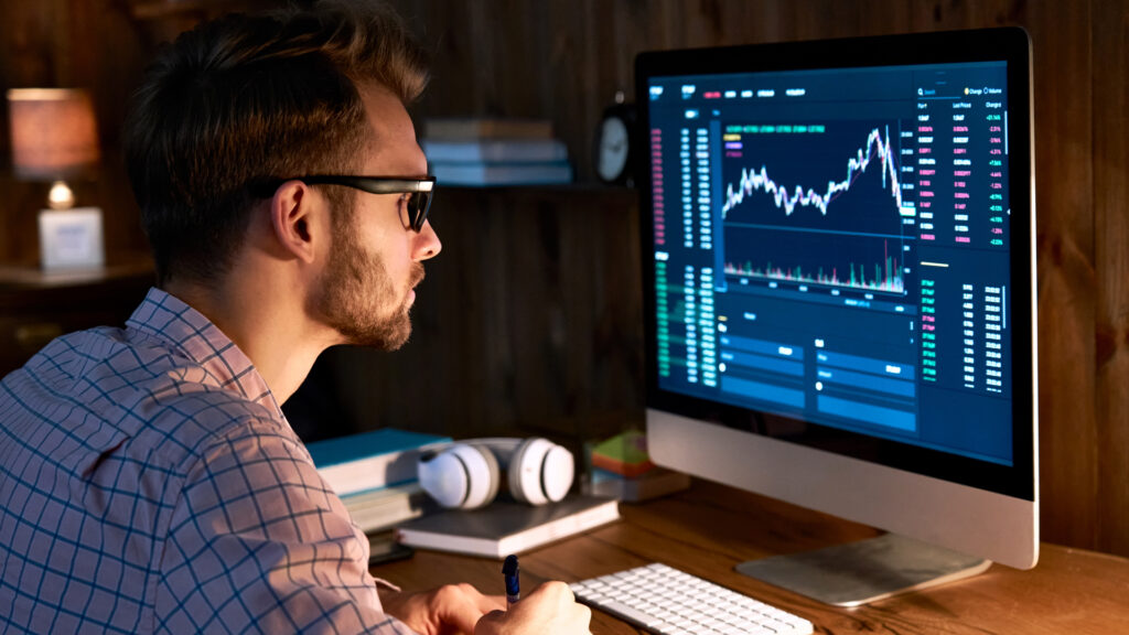 A man looking at graphs and data on a computer screen.