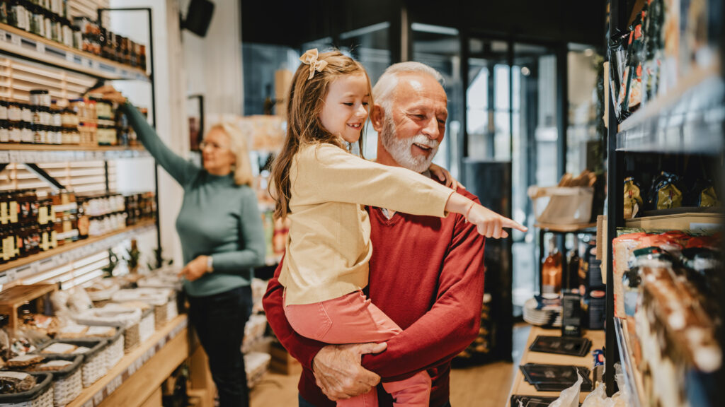 A grandfather grocery shopping with his granddaughter.