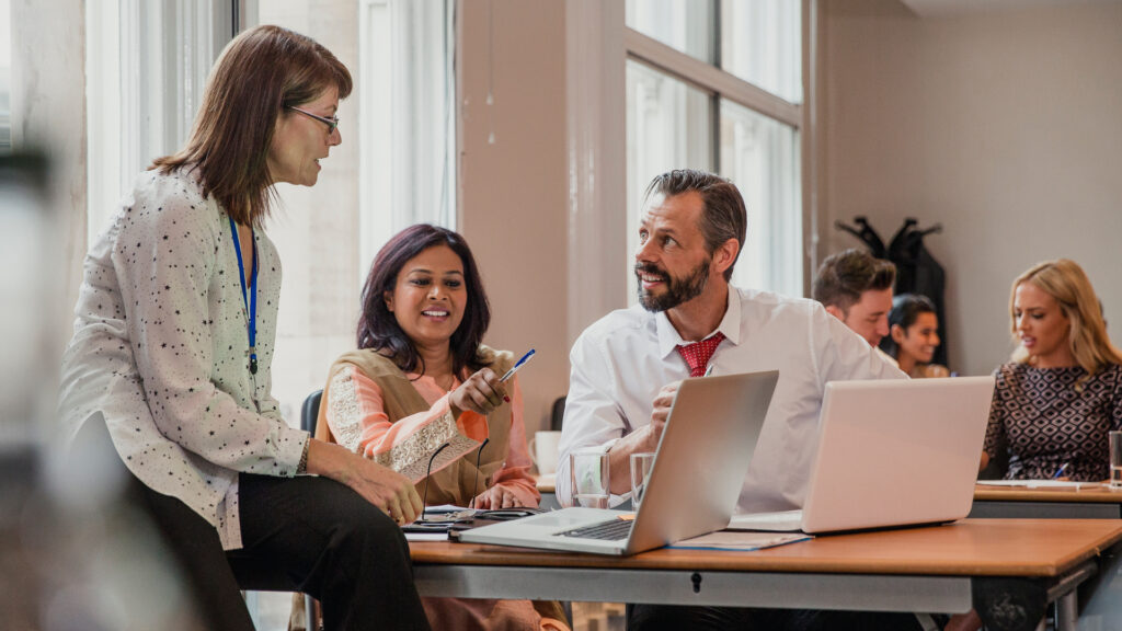 A group of workers gathered around laptops.