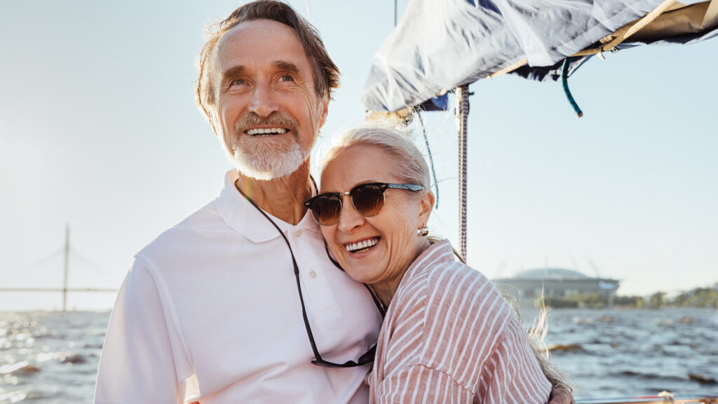 An older couple hugging on a boat.