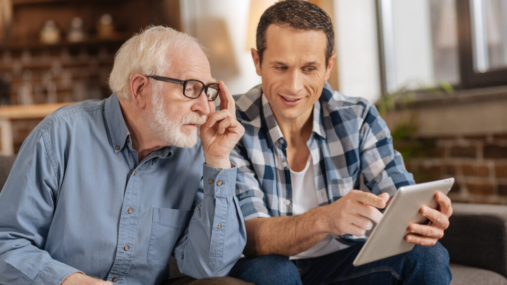 Young man showing his elderly father something on a tablet