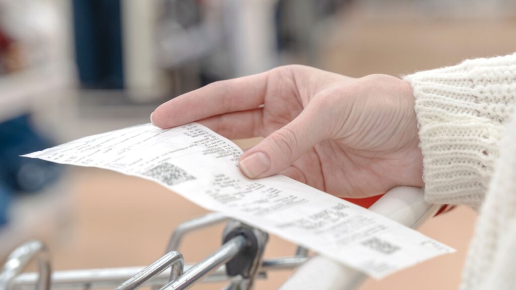 A woman looking at a receipt while shopping.