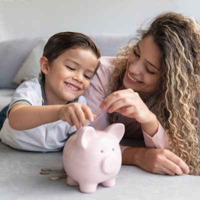 Portrait of a happy mother and son saving money in a piggybank and smiling - home finances concepts